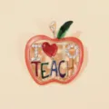 Detailed macro shot of apple brooch featuring 'I Love Teach' enamel and sparkling rhinestones - Graduation Apple Brooch / Red