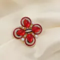 Gros plan d'une broche croix style cour vintage avec pierres rouges et perles blanches - Rouge