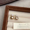 Primo piano di orecchini a perno con perla champagne e zircone in un portagioie. - Orecchini a Lobo con Perla Champagne (R0054)
