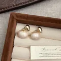 Detalle macro de elegantes pendientes de perlas de esmalte crema con detalles dorados. - Pendientes de Botón Ovalados de Esmalte (R0253)