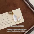 Dettaglio macro di un ciondolo a farfalla in madreperla naturale e zircone placcato oro - Ciondolo Farfalla Irregolare (A257) / Ciondolo Solo (Senza Catena)
