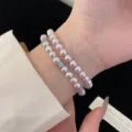 Elegantes zweireihiges Perlenarmband mit silberfarbenen Pavé-Abstandshalter am Handgelenk - Doppellagiges Manta Künstliches Perlenarmband (R0375) / Cremeweiß