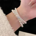 Close-up of elegant triple-layer pearl bracelet with sparkling zirconia clasp on wrist - R1321 White Triple Layer Style