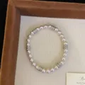 Detail view of a pink pearl bracelet with sparkling crystal spacers on a display tray. - Single Layer Manta Artificial Pearl Bracelet (R0303) / Pink