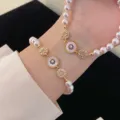 Close-up detail of elegant pearl bracelets with mother-of-pearl sun charms on a wrist. - Natural Shell Style (R0063) / White