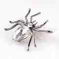 Gedetailleerde weergave van een vintage spinnenbroche met een groot druppelkristal. - Gun Black en Wit