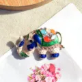 Détail d'une broche éléphant en émail coloré avec pierres œil de chat brillantes - Coloré