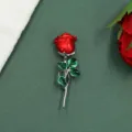 Close-up detail of a vintage red rose brooch with green leaves on a textured green background - Red Rose Style B
