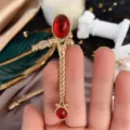 Detail einer goldenen Vintage-Brosche mit roten Steinen die die Größe zeigt - Rot