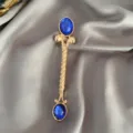 Detaillierte Nahaufnahme einer Vintage Goldenen Brosche mit blauen Steinen auf Seide - Blau
