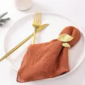 Elegante orangefarbene Leinenserviette mit goldenem Serviettenring in Blattform auf Teller - Orange