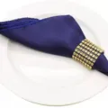 Royal blue satin cloth napkin with gold rhinestone ring for elegant hotel table decor. - Deep purple