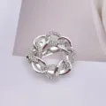 Nahaufnahme einer silbernen Brosche mit ineinandergreifenden Ketten und Kristallen - Silber