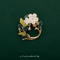 Close-up of an elegant enamel flower wreath brooch featuring white petals and a pearl drop - Flower Garland