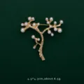 Close-up of gold-plated tree branch brooch with elegant white pearls on green background. - Plum
