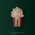 Close-up detail of a vintage popcorn brooch pin featuring pearls and red rhinestones. - Popcorn