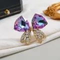 Dettaglio ravvicinato di un'elegante spilla a fiocco in cristallo viola con finiture dorate. - Stile Fiocco di Nastro di Cristallo / Iridescente