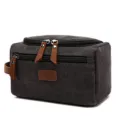 Close-up of a durable charcoal canvas toiletry bag with premium brown leather zipper pulls. - Black