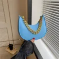 Elegante bolso de media luna en fieltro azul claro con textura de lagarto y cadena dorada - Azul claro
