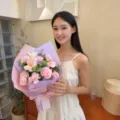 Jeune femme asiatique tenant un bouquet cadeau de roses roses et d'œillets en savon - Avec Grand Sac à Fenêtre / Rose Violet