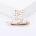 Detailed macro view of a gold-plated sailboat brooch with elegant white enamel sails - Gold White