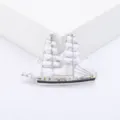 Macro detail shot of an elegant silver sailing ship brooch with white enamel sails. - Silver