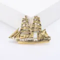 Close-up detail of a vintage golden sailing ship brooch with intricate masts and sails - Gold