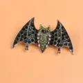 Detailed view of a bat-shaped brooch with green rhinestones on a warm orange background - Silver Bat Style (Brooch 4) / Silver Base Green Rhinestone Style (Brooch 4)