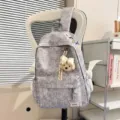 Vista detallada de una mochila gris jaspeado con textura arrugada y llavero de peluche. - Sin colgante / Gris