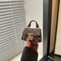 Detail view of a luxury mini brown patterned crossbody bag with gold chain strap - Coffee
