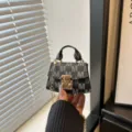 Macro view of mini monogram handbag with elegant gold chain and secure clasp closure. - Black