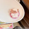 Detailed macro shot of a cute cartoon cat phone grip on a white scalloped plate. - Pajama Cat Magnetic Stand / Single Stand