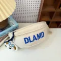 Close-up of a cream nylon chest bag with blue DLAMD print and a cute plush dog charm detail - Off White