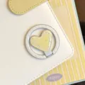 Détail macro d'un support de téléphone MagSafe jaune en forme de cœur avec étoiles - Support Magnétique Cœur Doré / Support Unique / Étoile Jaune Rayure Blanche