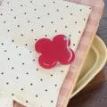 Gros plan d'un support de téléphone pliable en forme de fleur rouge sur un tissu à motifs - Support Trèfle Rouge