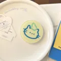 Gros plan d'un support de téléphone rond jaune avec un joli chat bleu et une poire verte. - Support Chat Poire / Support Unique