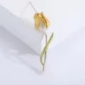Detailed close-up of an elegant gold and pearl-white tulip brooch pin with green leaf - Yellow