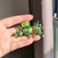 Close-up of a sparkling crystal owl brooch with green rhinestones on a golden branch. - Three Owls Brooch (XZ0457-2) / Green