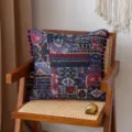 Bohemian ethnic patchwork pillow cover with purple pompom trim decor on wooden chair. - Purple
