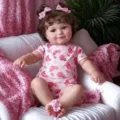 20 inch Maddie reborn baby doll wearing a pink heart-patterned romper with hair bows - Heart Bow Romper Set / 20 Inch Full Body Silicone
