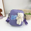Detalle de bandolera de nailon violeta decorada con un peluche de oso blanco y suave - 16*20*6 / Púrpura