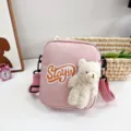 Detalle de un bolso bandolera de nailon rosa con un oso de peluche y parche 'STAY in' - 16*20*6 / Rosa