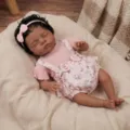 Detailed view of realistic sleeping reborn baby doll Irys wearing a pink floral romper and bow - 48cm / Cloth Body Style / Pink Floral