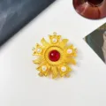 Detailed close-up of a vintage golden sunburst brooch featuring a red center and pearls - Radiant Sunflower Style / Red