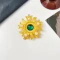 Detailed close-up of vintage heraldic gold brooch with green glass and pearls. - Sun Flower Cross Style / Green