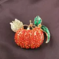Close-up of a retro pumpkin brooch with red rhinestones and green enamel leaves. - Pumpkin Style (B5)