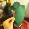 Dettaglio di spilla a fiore vintage con cristalli e perla su espositore - Stile Rosso Rosa e Perla Arancione