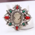 Vista detallada del broche camafeo vintage con pedrería roja y verde en acabado dorado - Camafeo Vintage (AL680071855347) / Multicolor