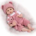 Close-up of a 22-inch reborn baby doll wearing a pink knitted romper on white fur - Pink / 55 cm