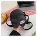Primer plano de un bolso bandolera de nailon negro con un logotipo fashion plateado - 7*13*16 / Negro